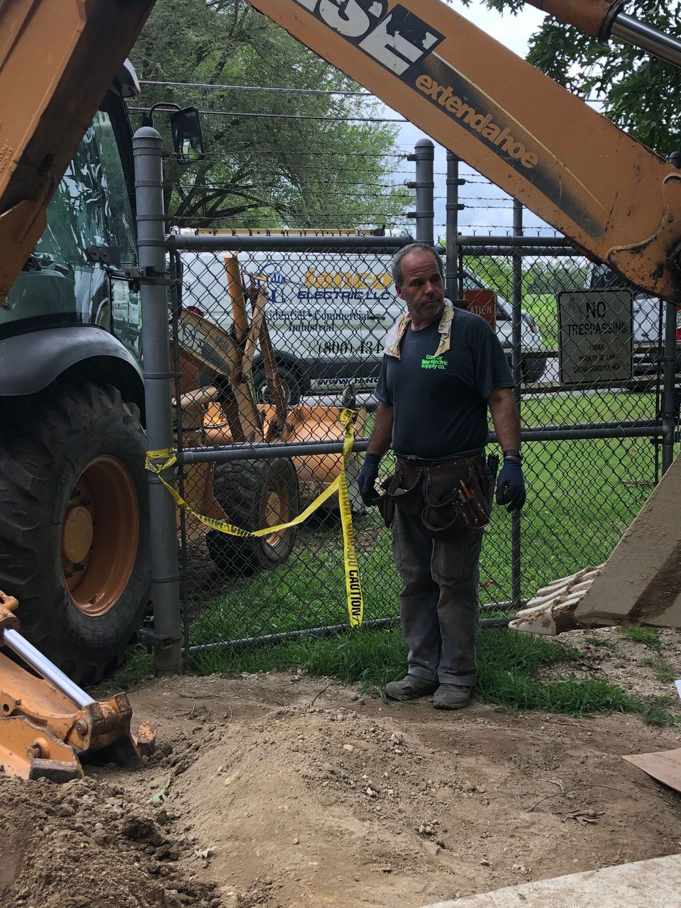 A man is standing in front of a case construction vehicle.
