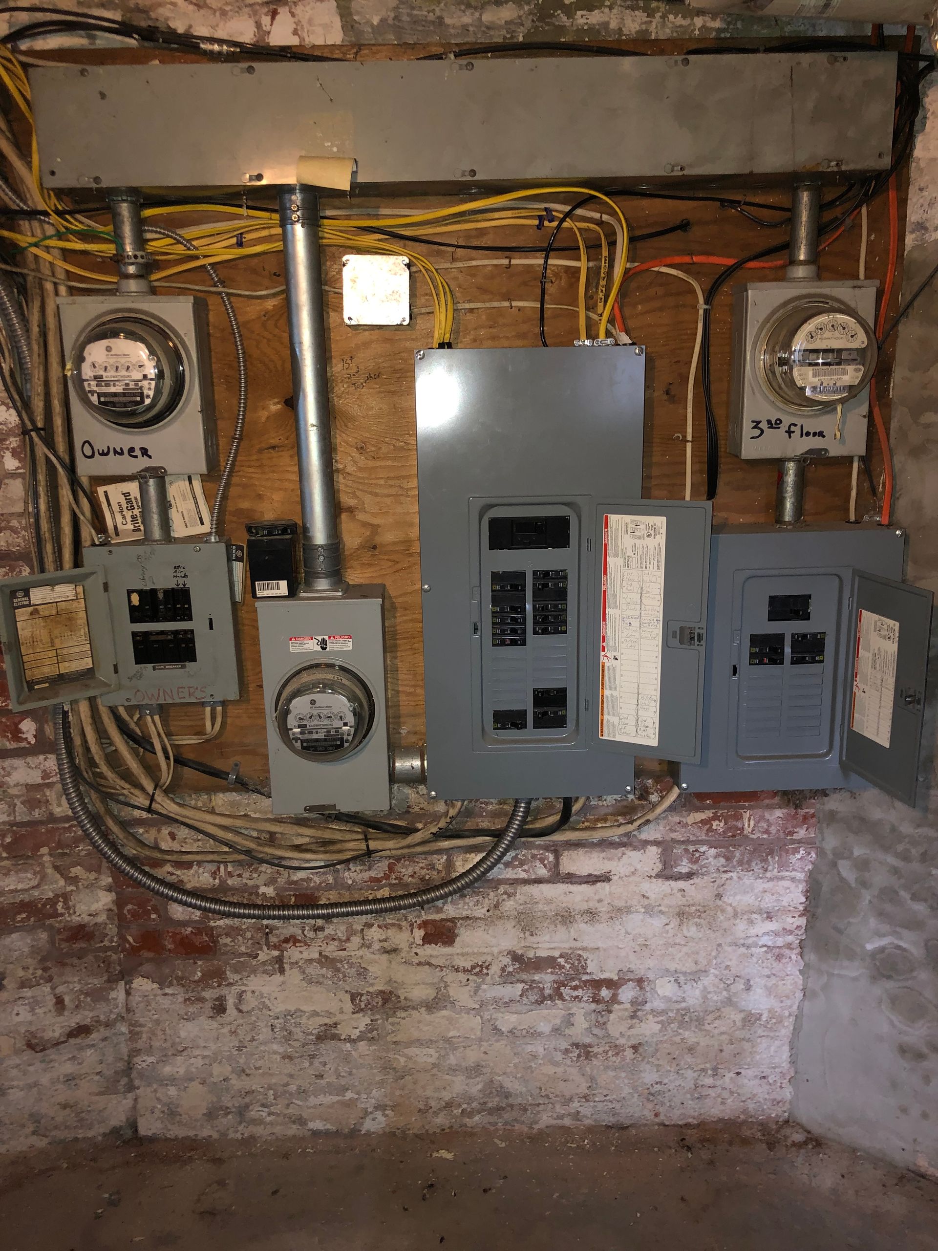 A brick wall with electrical panels and meters on it.