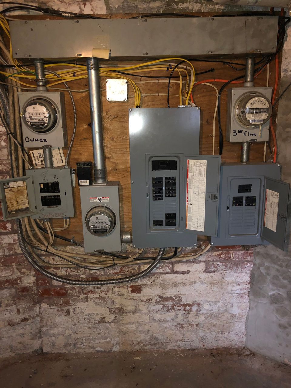 A brick wall with electrical panels and meters on it.