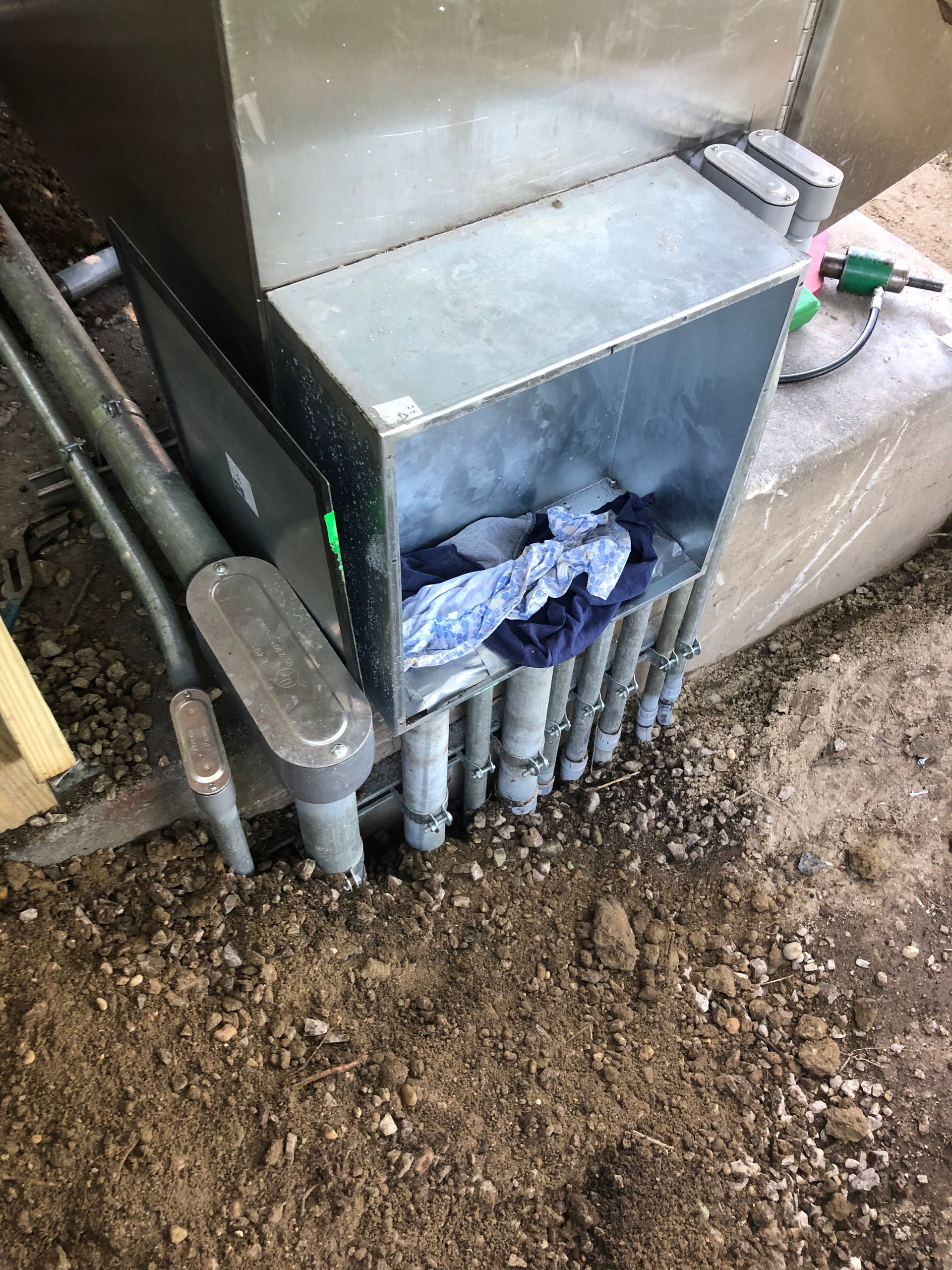 A box filled with pipes is sitting on top of a pile of dirt.