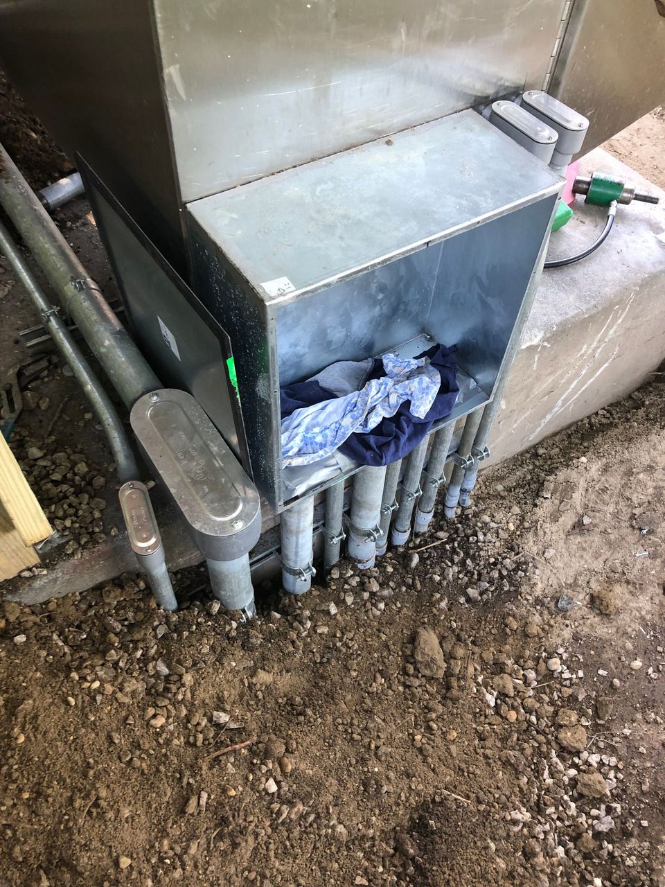 A box filled with pipes is sitting on top of a pile of dirt.