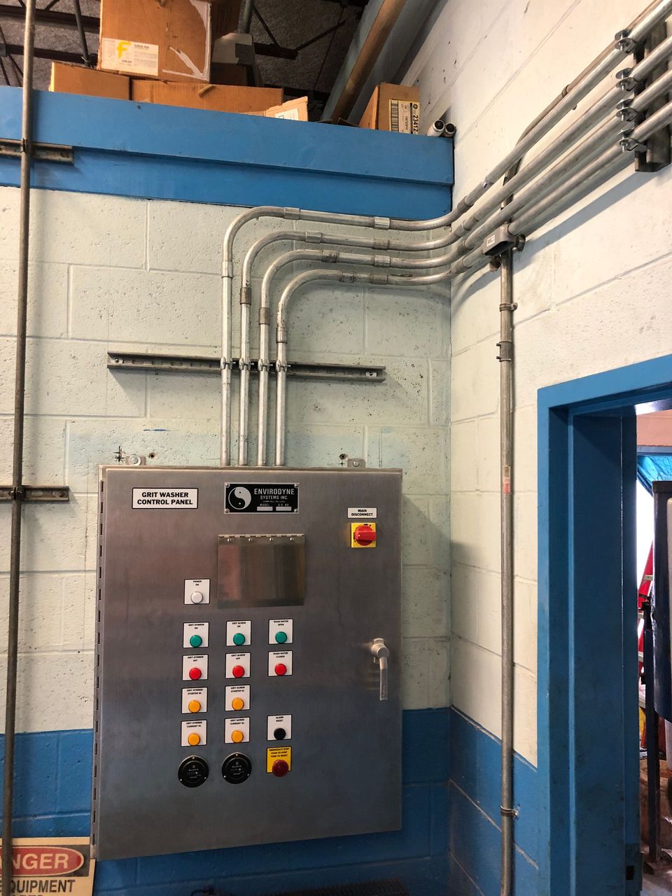 A stainless steel control panel is hanging on a brick wall