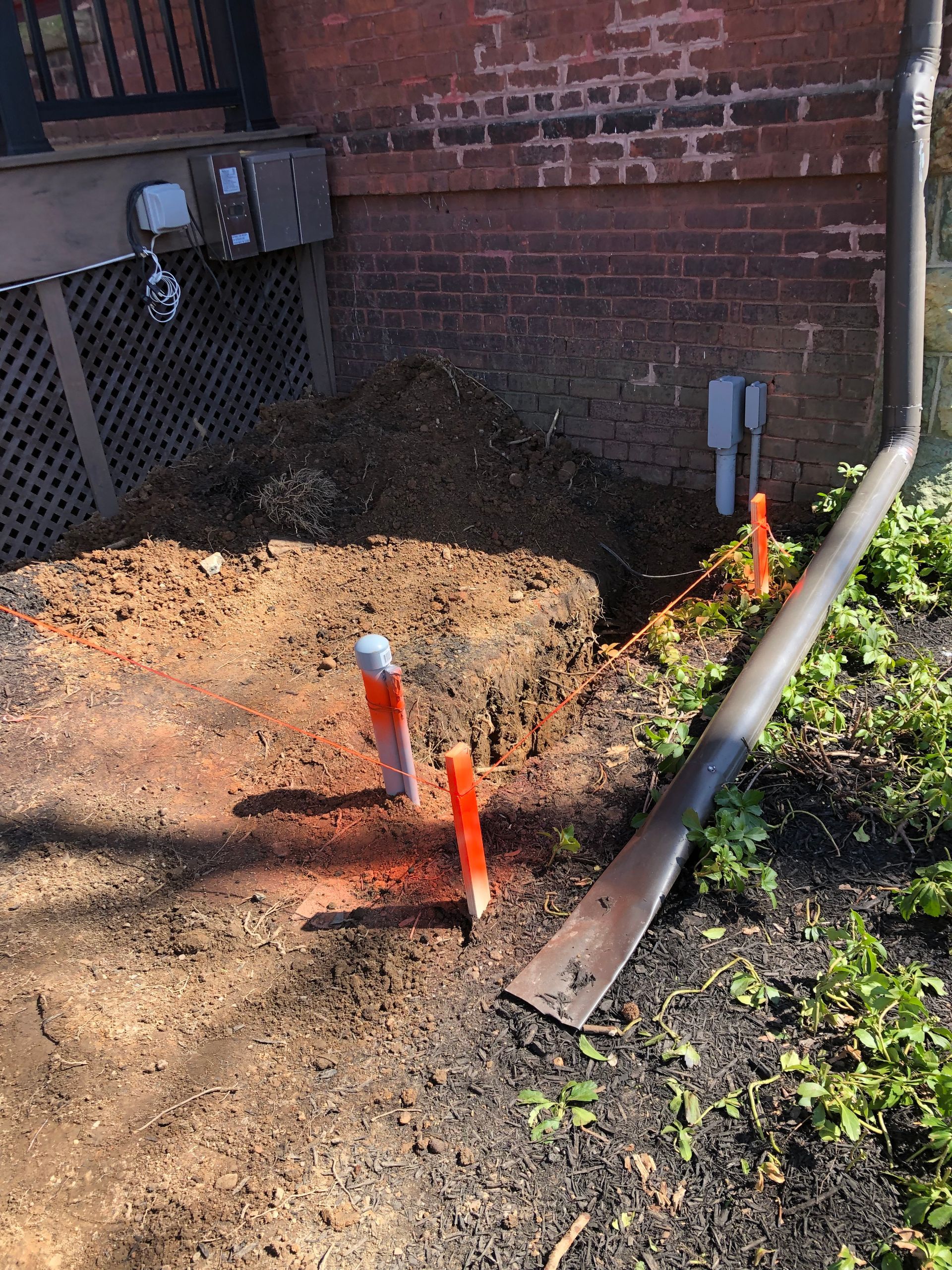 A shovel is sitting in the dirt next to a brick wall.