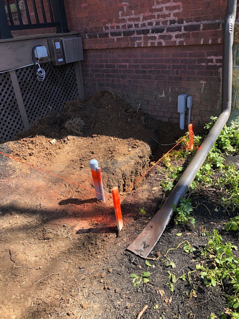 A shovel is sitting in the dirt next to a brick wall.