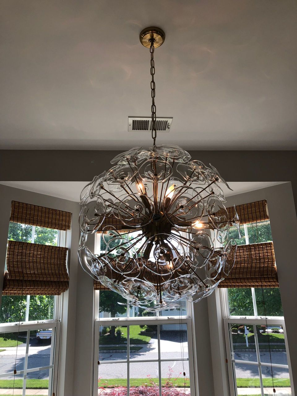 A chandelier is hanging from the ceiling in front of a window.