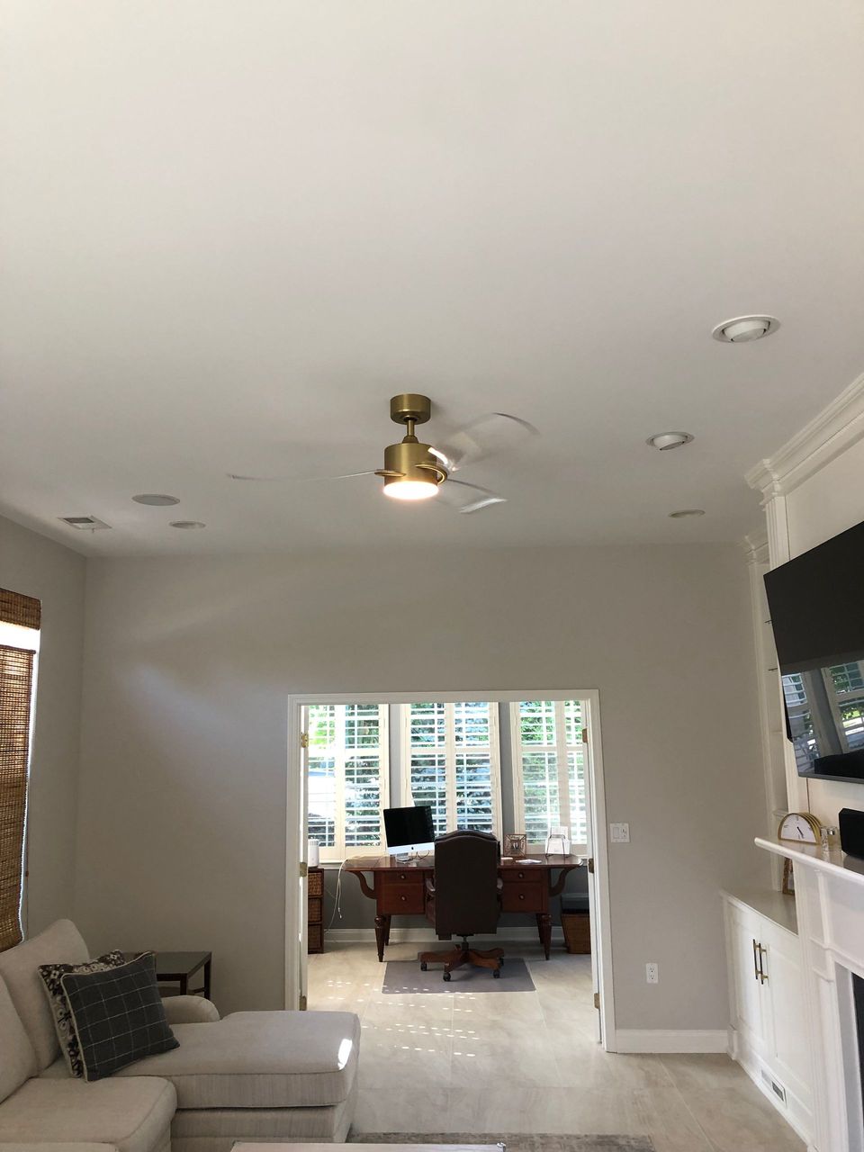 A living room with a ceiling fan and a desk