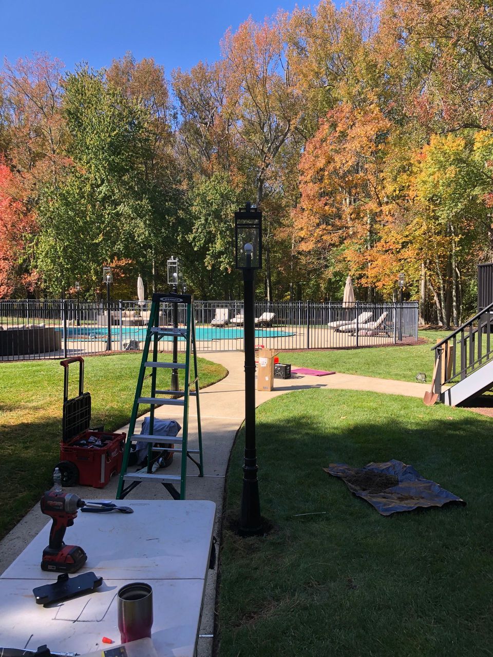 A ladder is sitting next to a lamp post in a backyard.