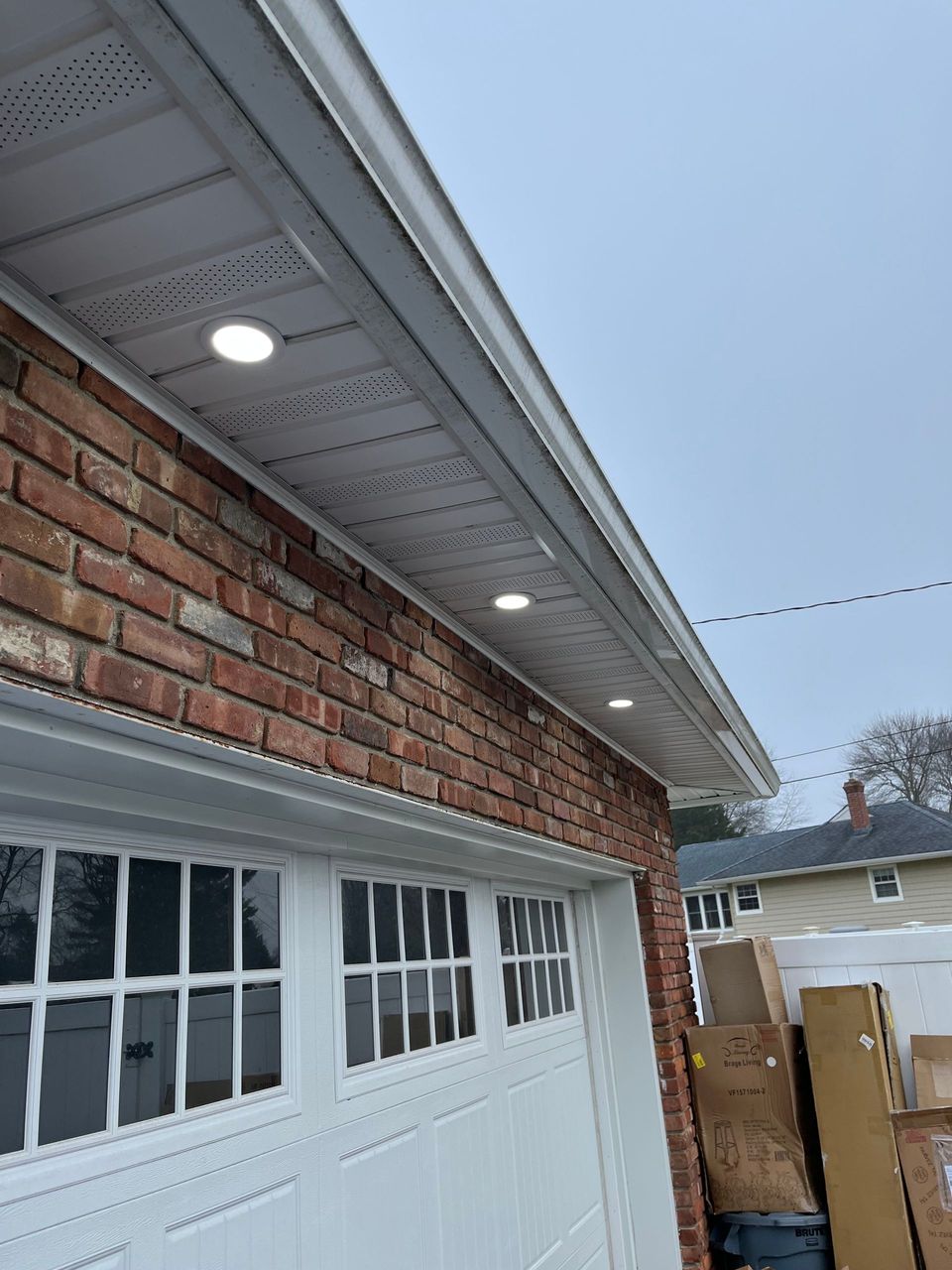 A brick house with a white garage door and lights on the roof.