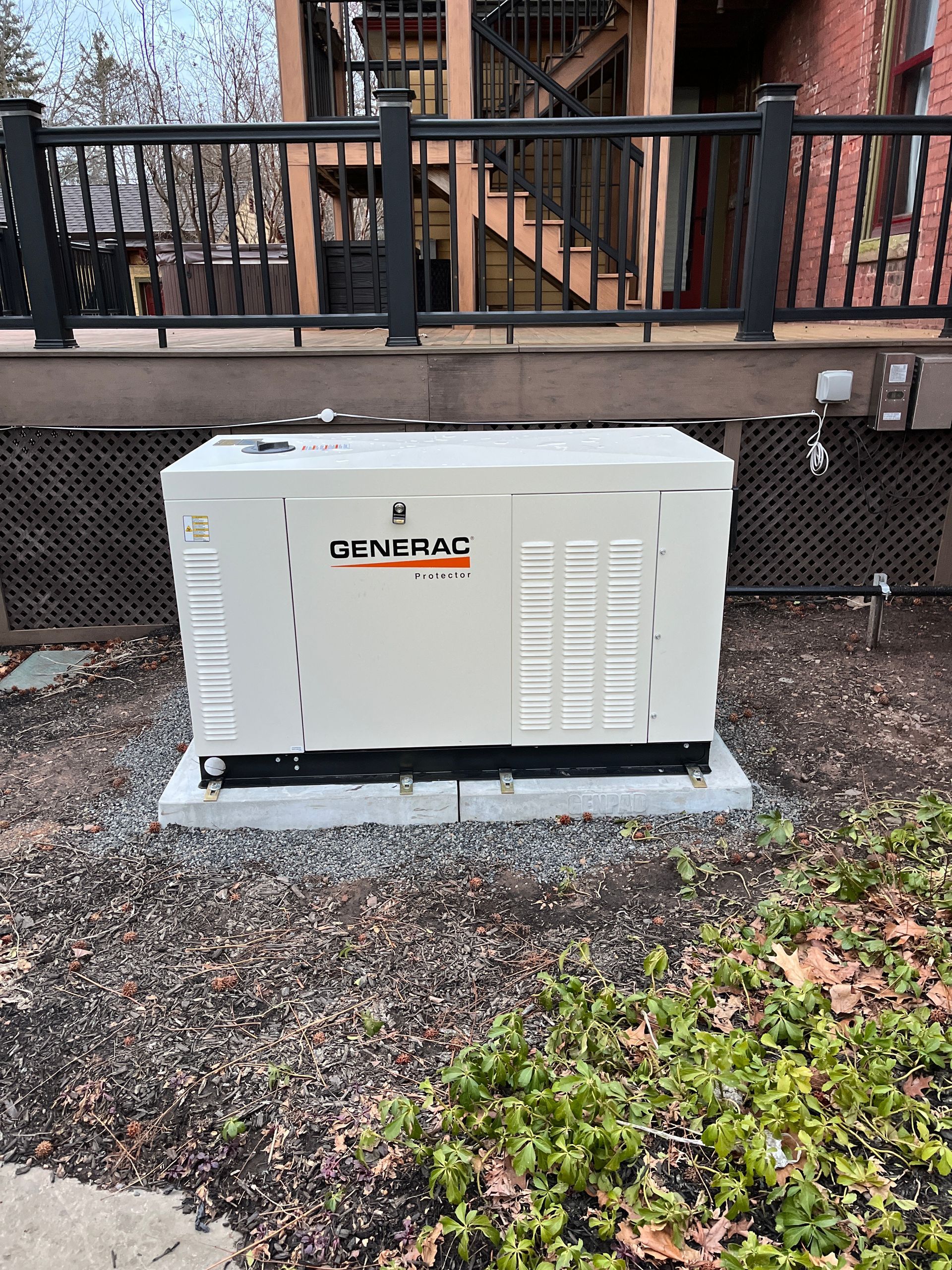 A generator is sitting in the grass in front of a house.