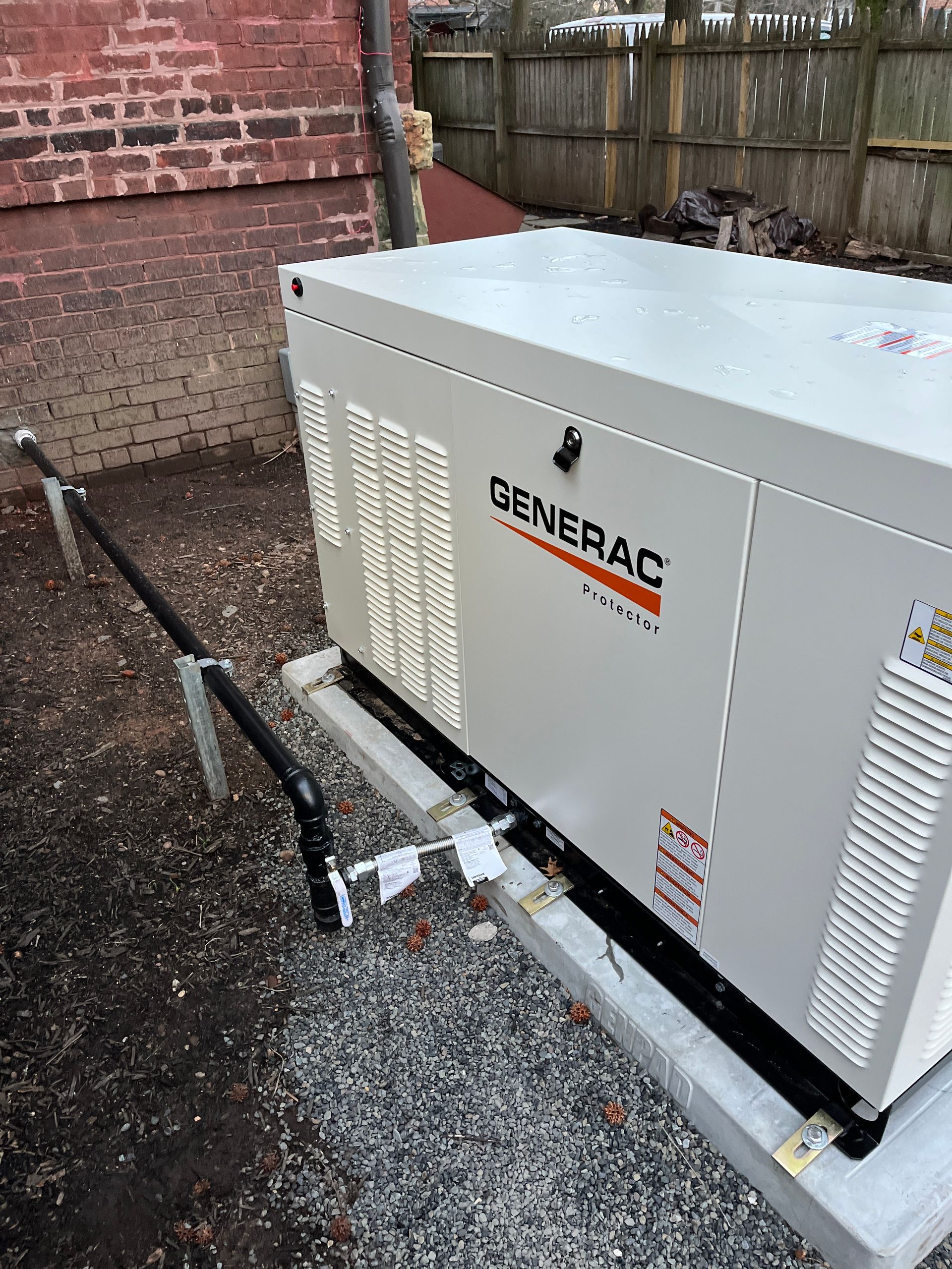 A generator is sitting on top of a trailer in front of a brick building.