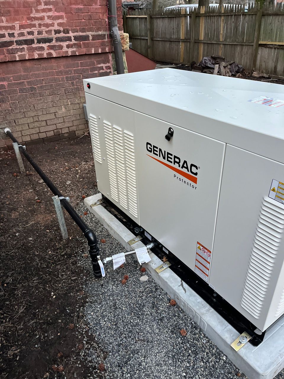 A generator is sitting on top of a trailer in front of a brick building.