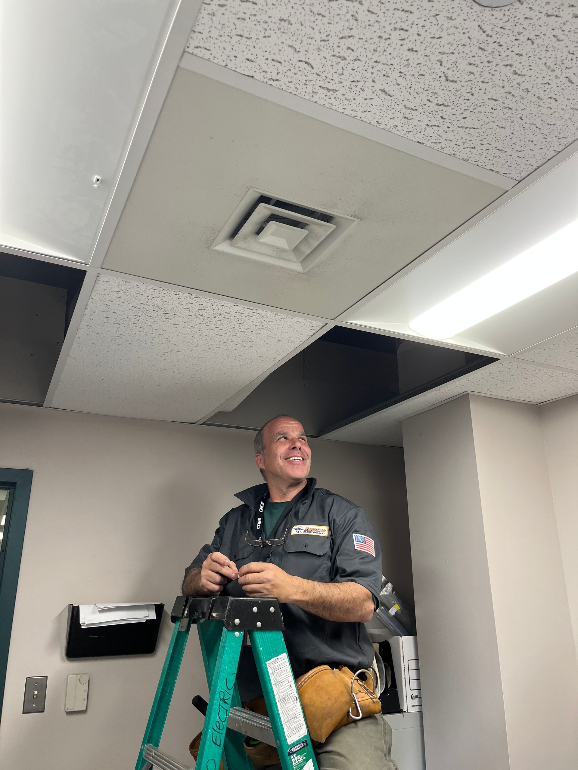 A man is standing on a ladder working on a ceiling.