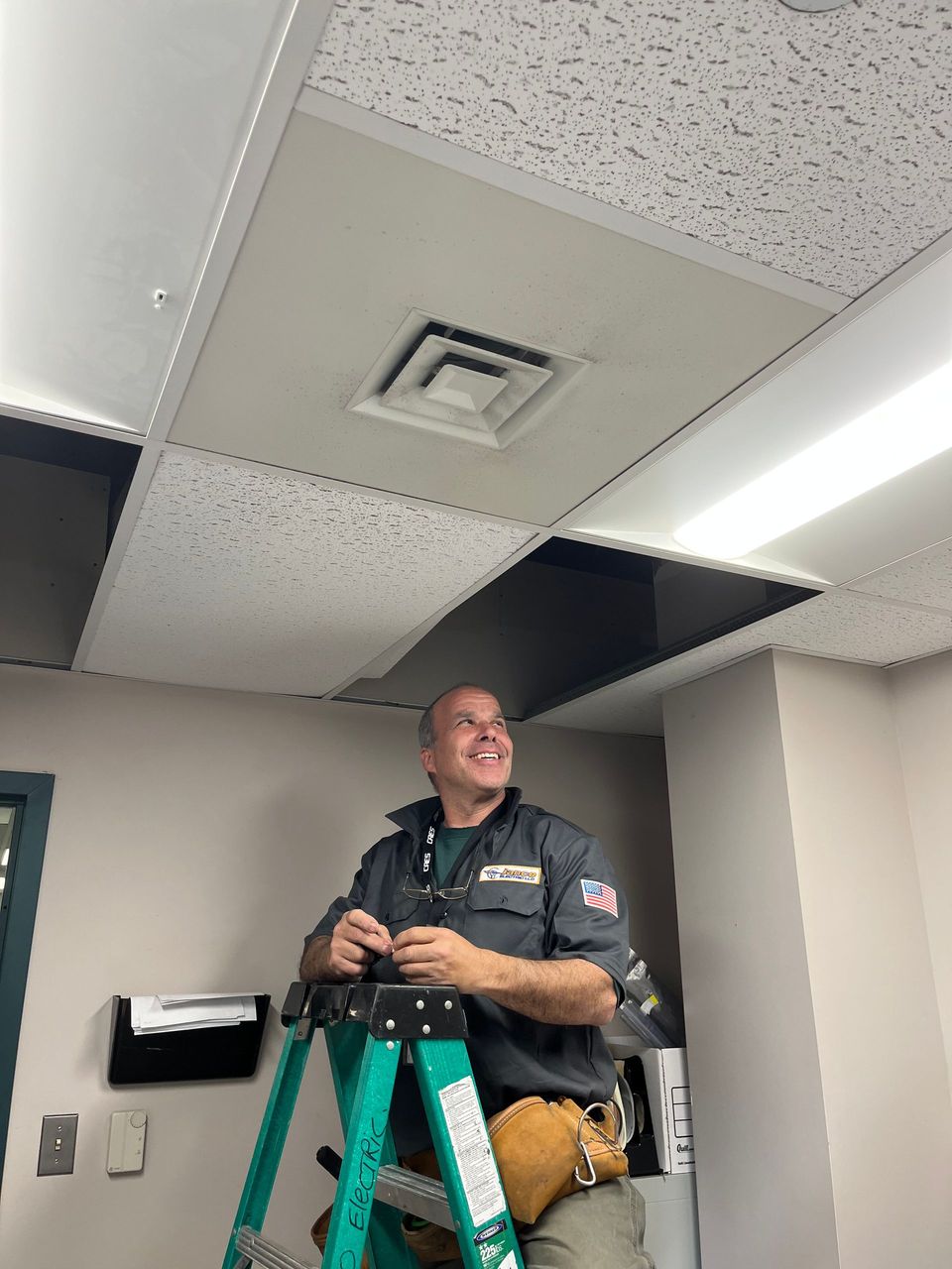 A man is standing on a ladder working on a ceiling.