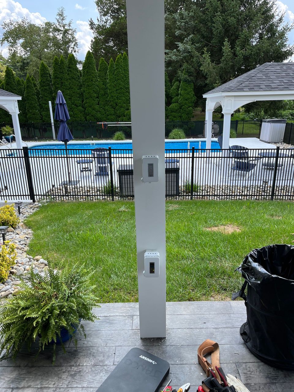 A white pole is sitting on a patio next to a pool.