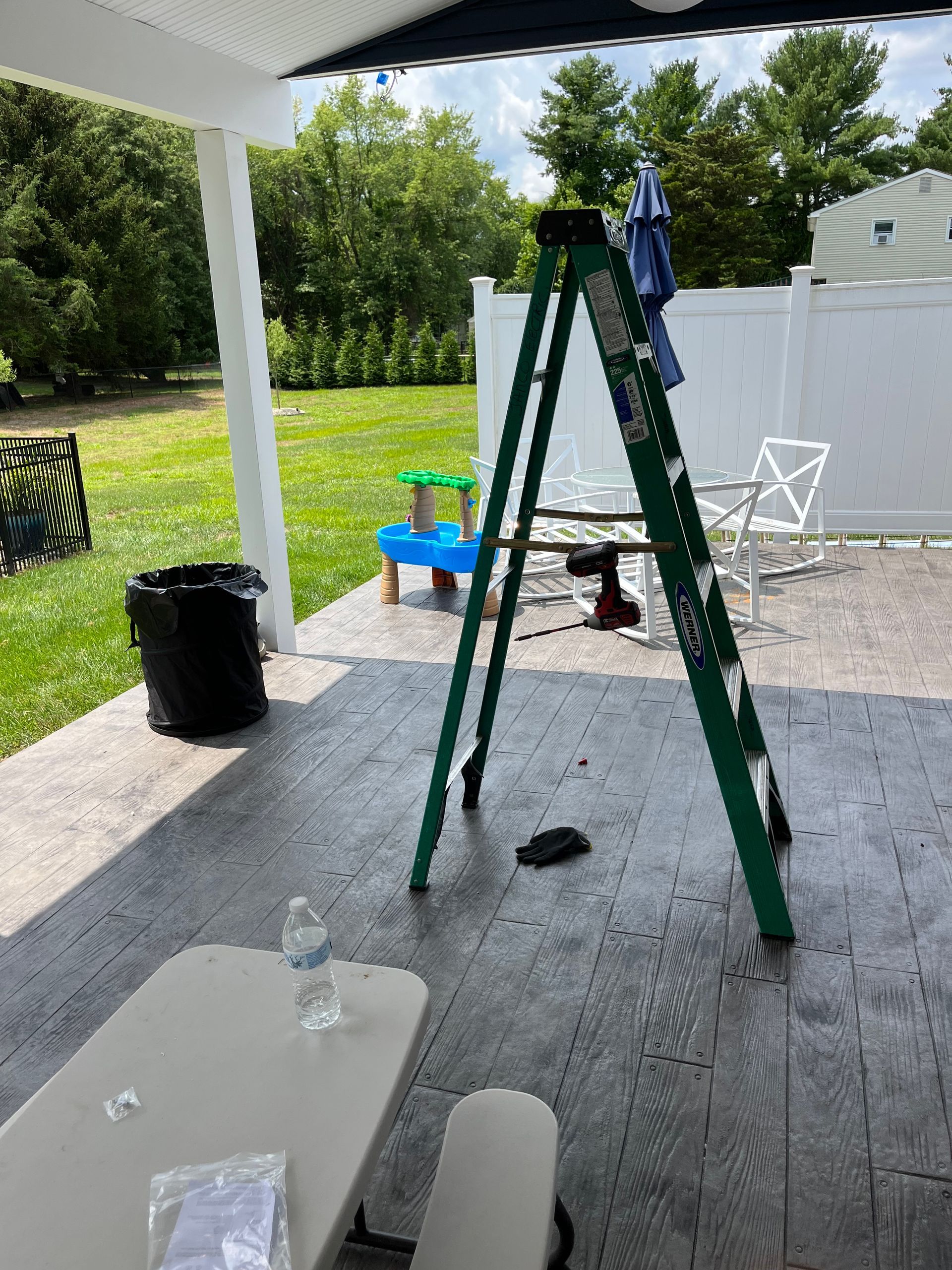 A ladder is sitting on top of a patio next to a table.