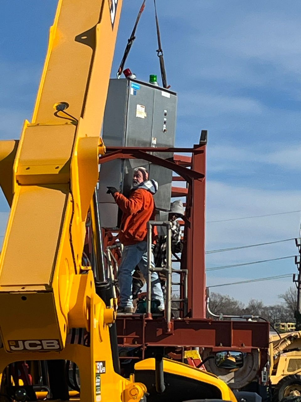 A man is standing on top of a jcb crane