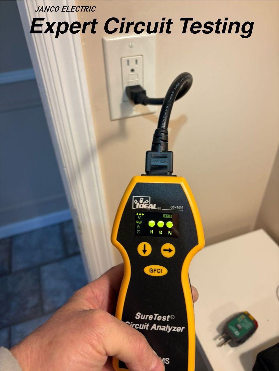 Hand holding a yellow electrical outlet tester plugged into a wall outlet under “Expert Circuit Testing” text