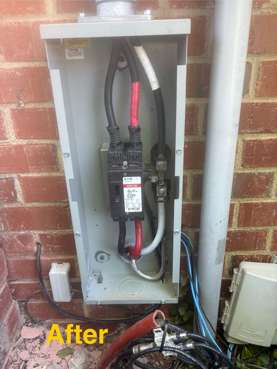 Open electrical panel on brick wall with exposed wiring and cables, labeled “After.”