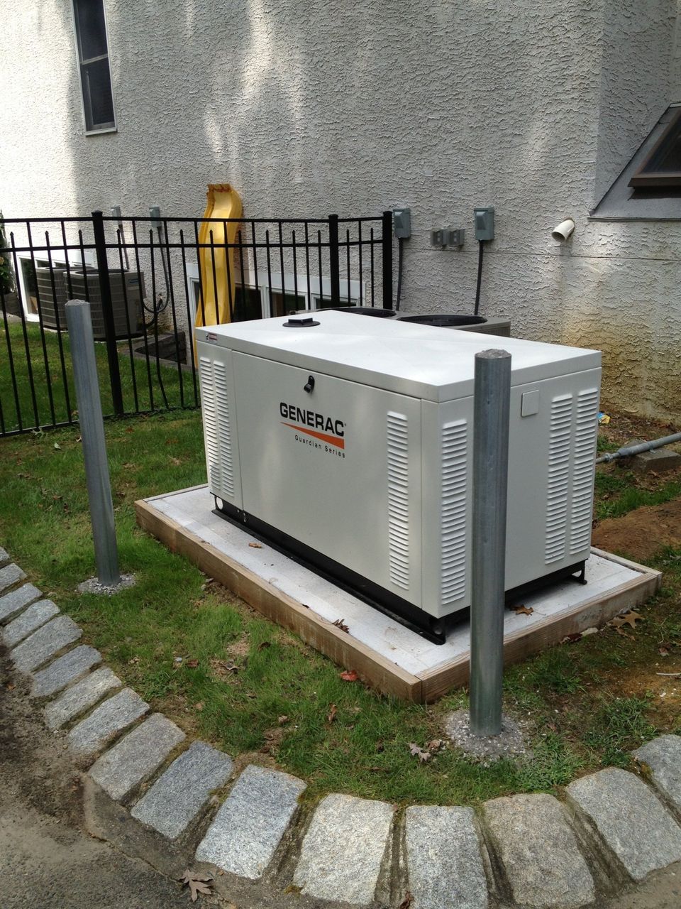 A generator is sitting in the grass in front of a building.