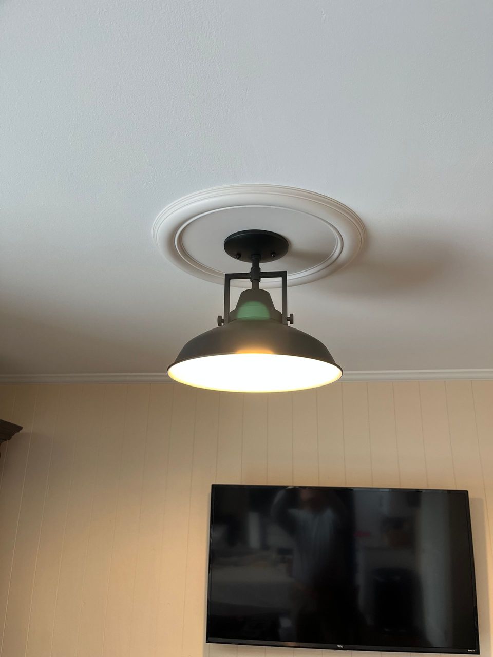 A living room with a ceiling light and a flat screen tv