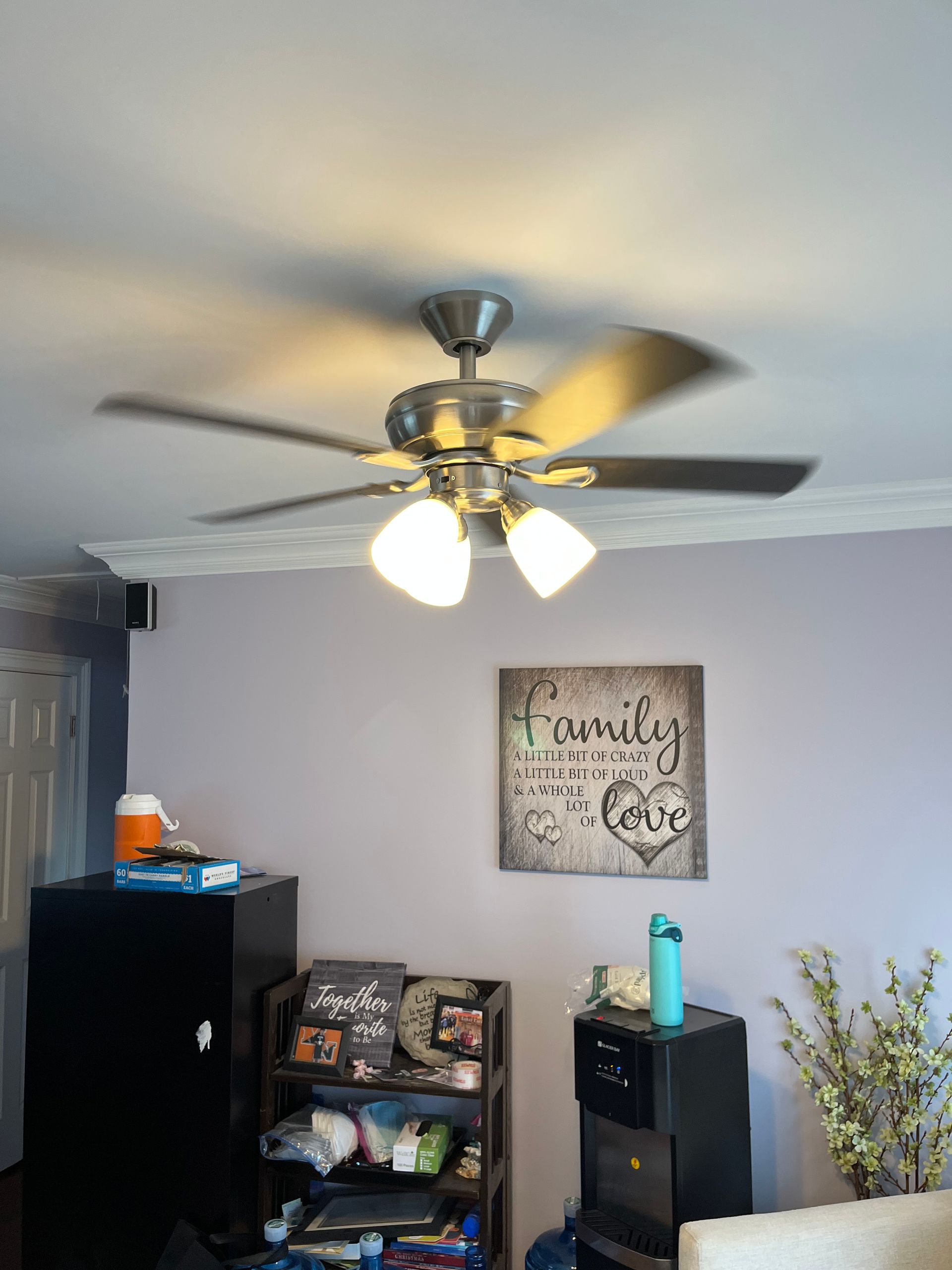 A living room with a ceiling fan and a sign that says family