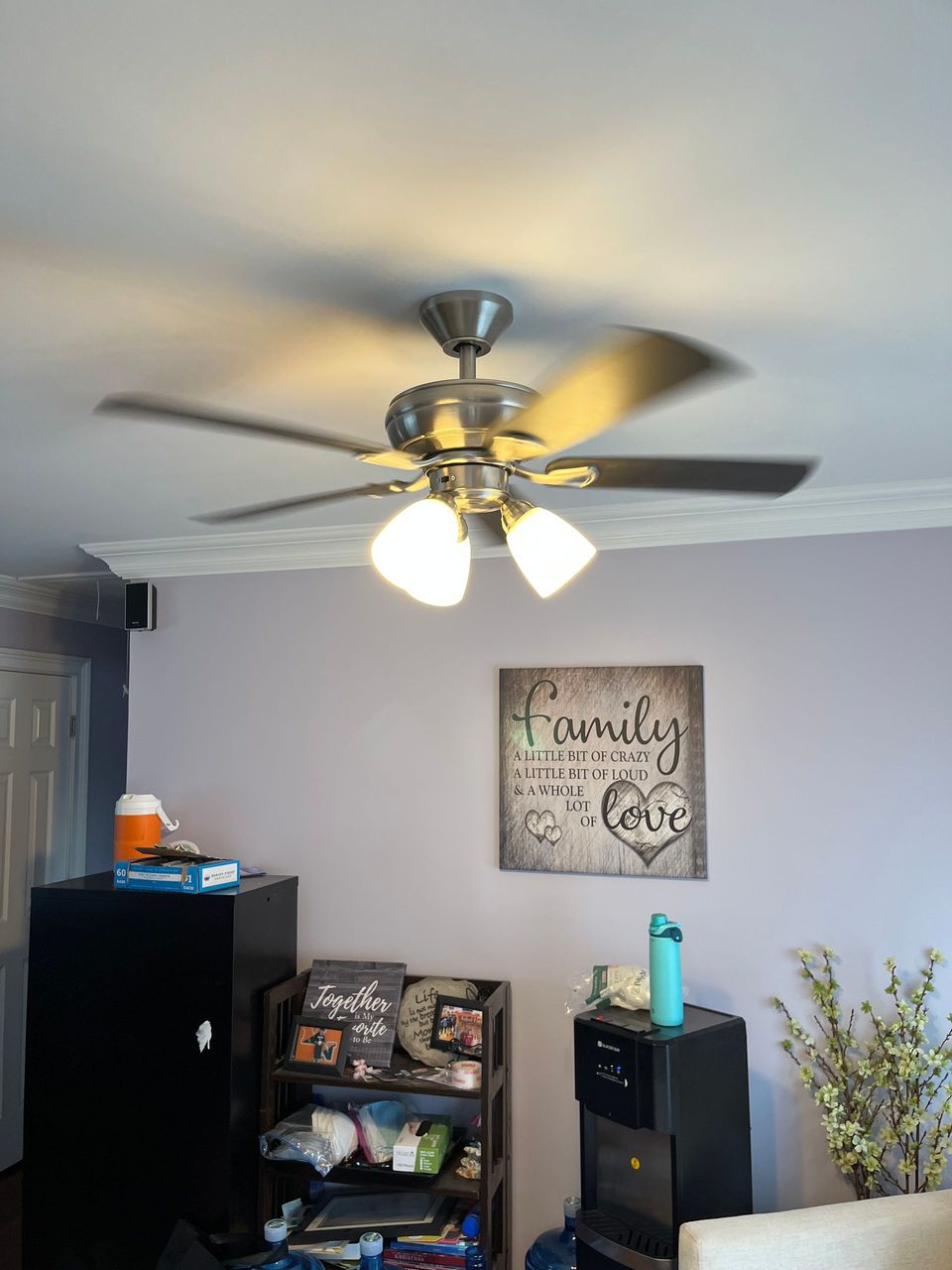 A living room with a ceiling fan and a sign that says family
