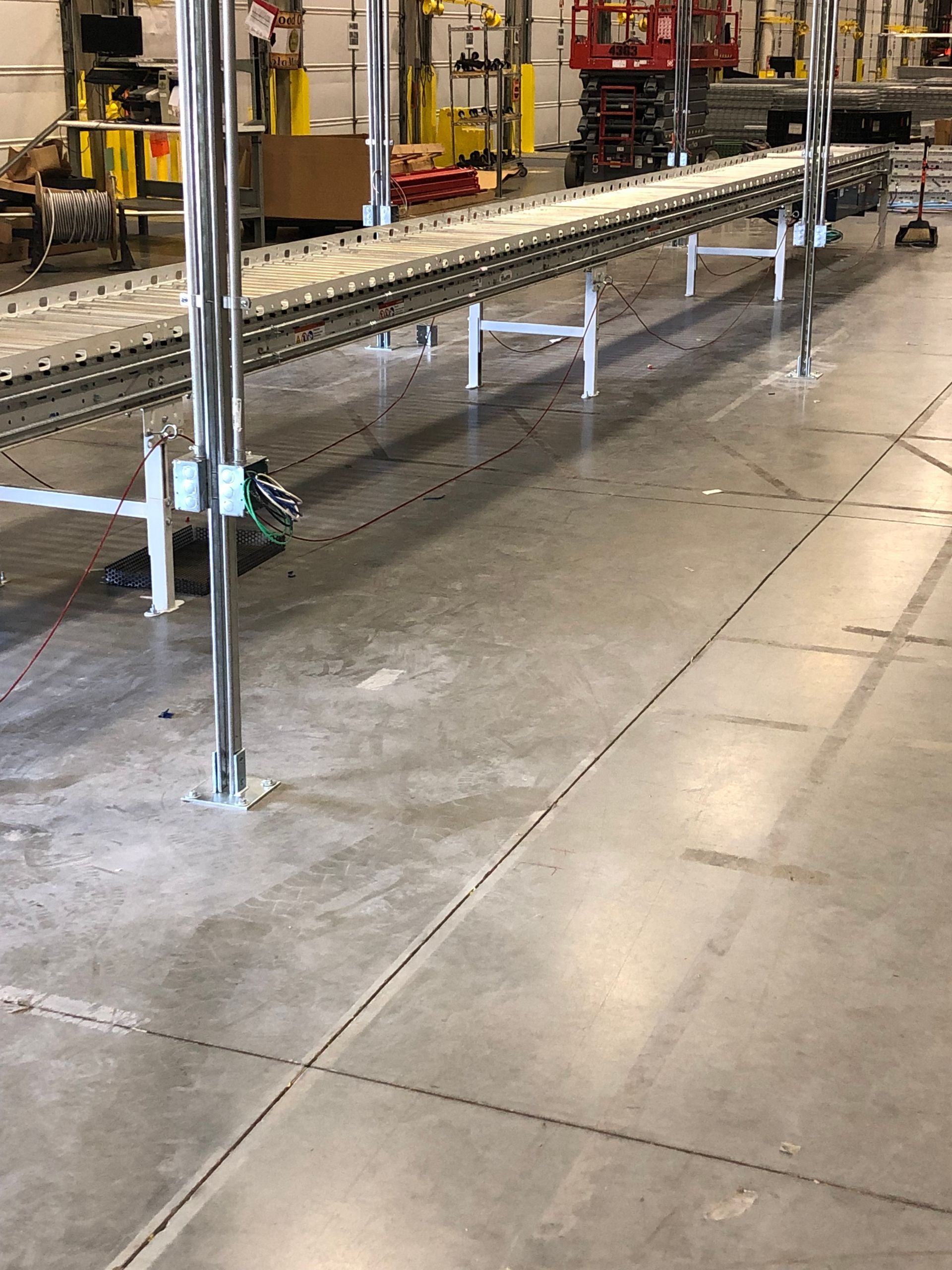 A conveyor belt is sitting on a concrete floor in a warehouse.