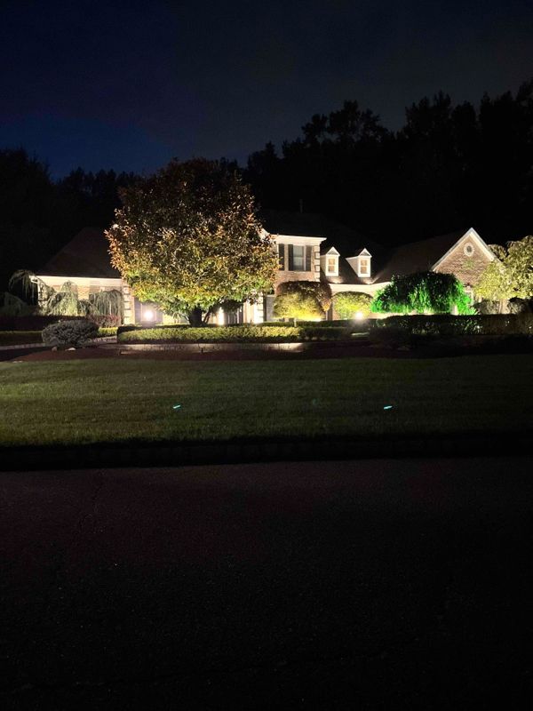 A large house is lit up at night with trees in the background.