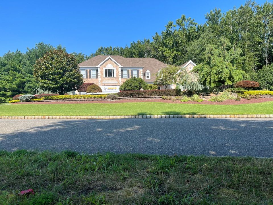 A large house is sitting on top of a lush green hillside surrounded by trees.