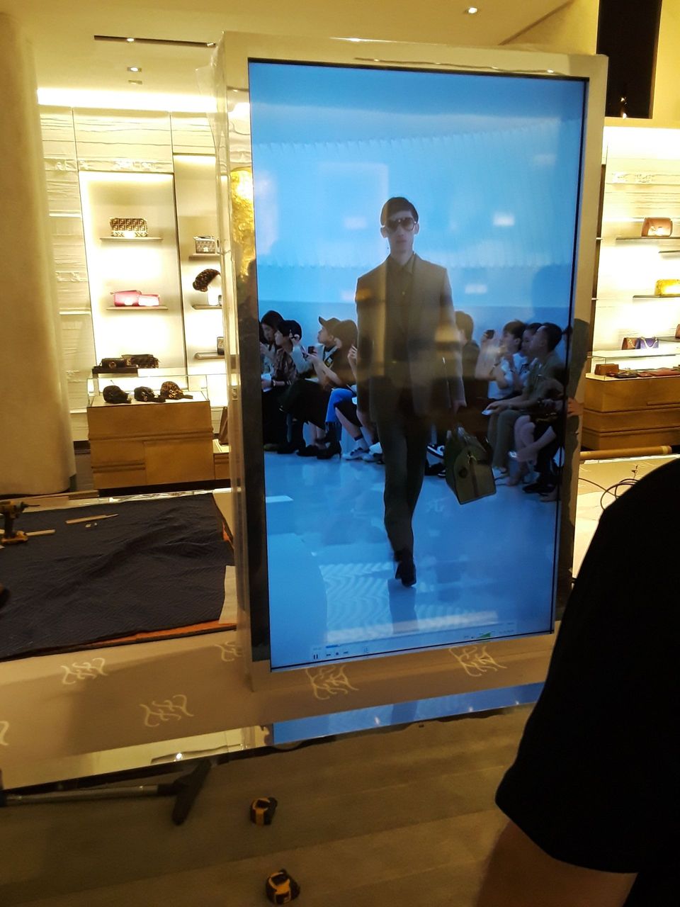 A man is walking down a runway on a screen in a store