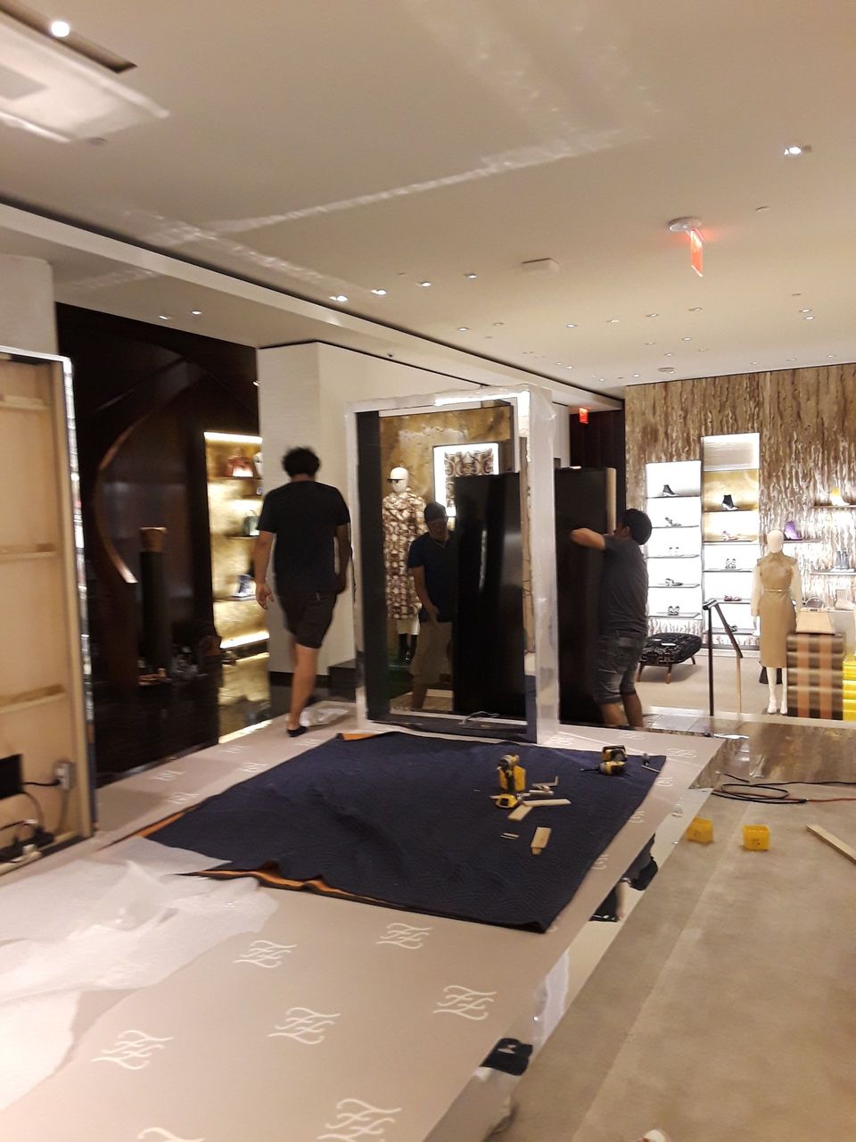 A group of people are working on a large mirror in a store.