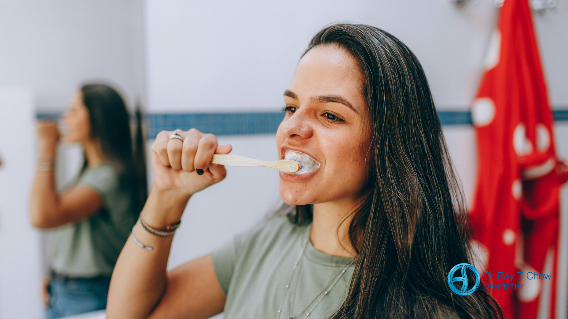 A woman is brushing her teeth in front of a mirror in a bathroom.