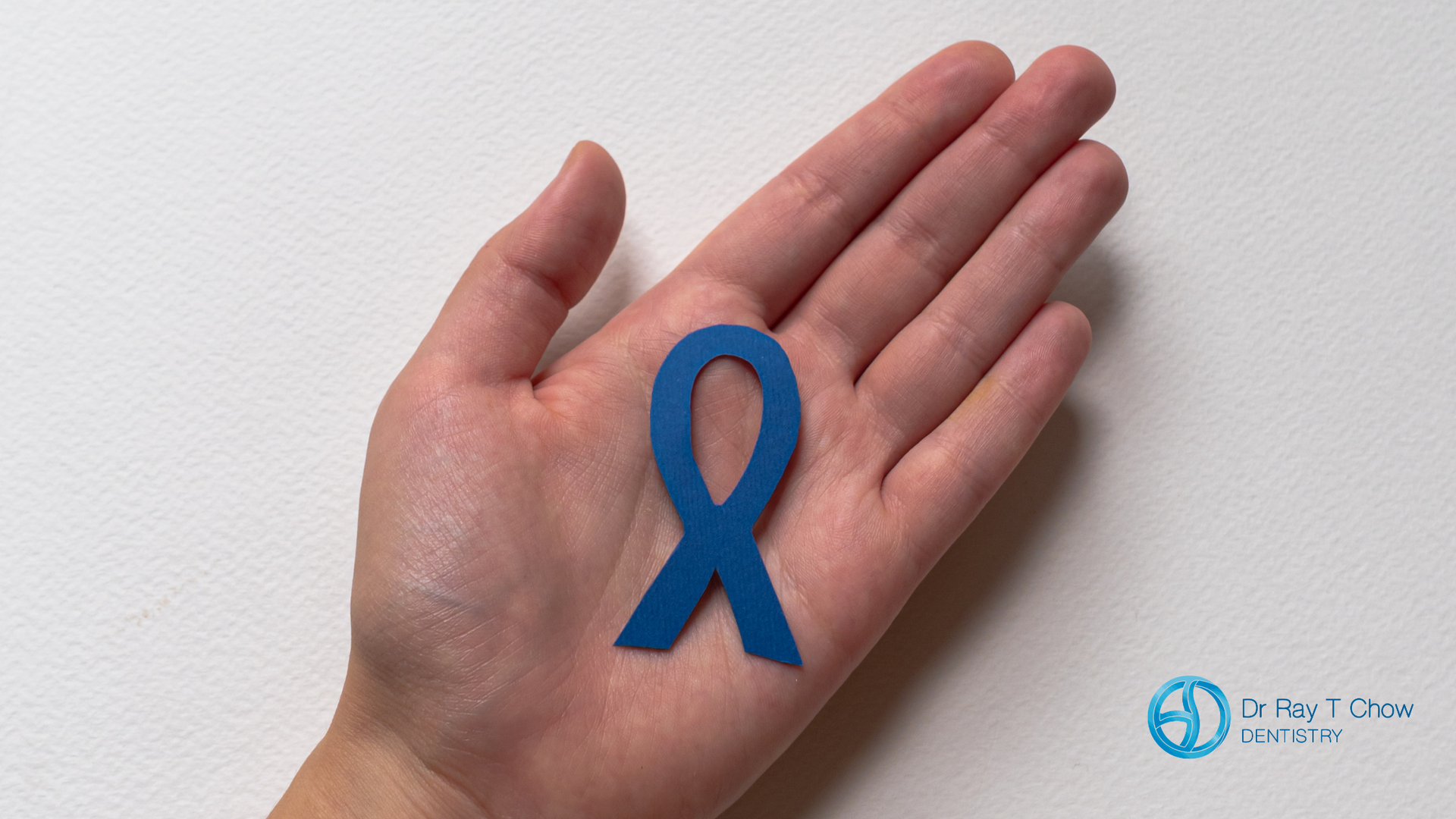 A person is holding a blue ribbon in their hand.