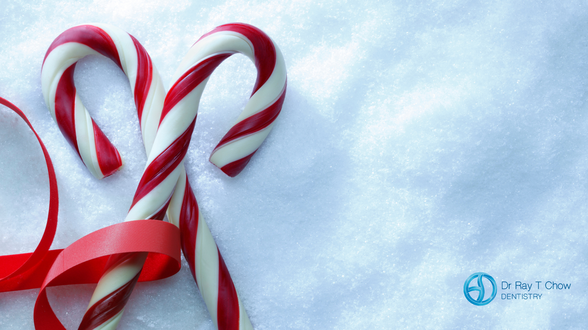 Two red and white candy canes tied with a red ribbon