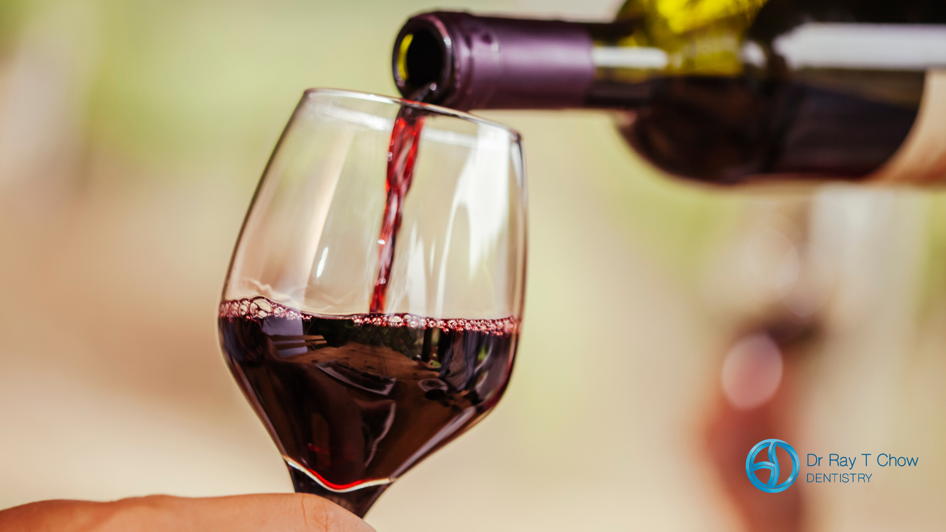 A person is pouring red wine into a glass.