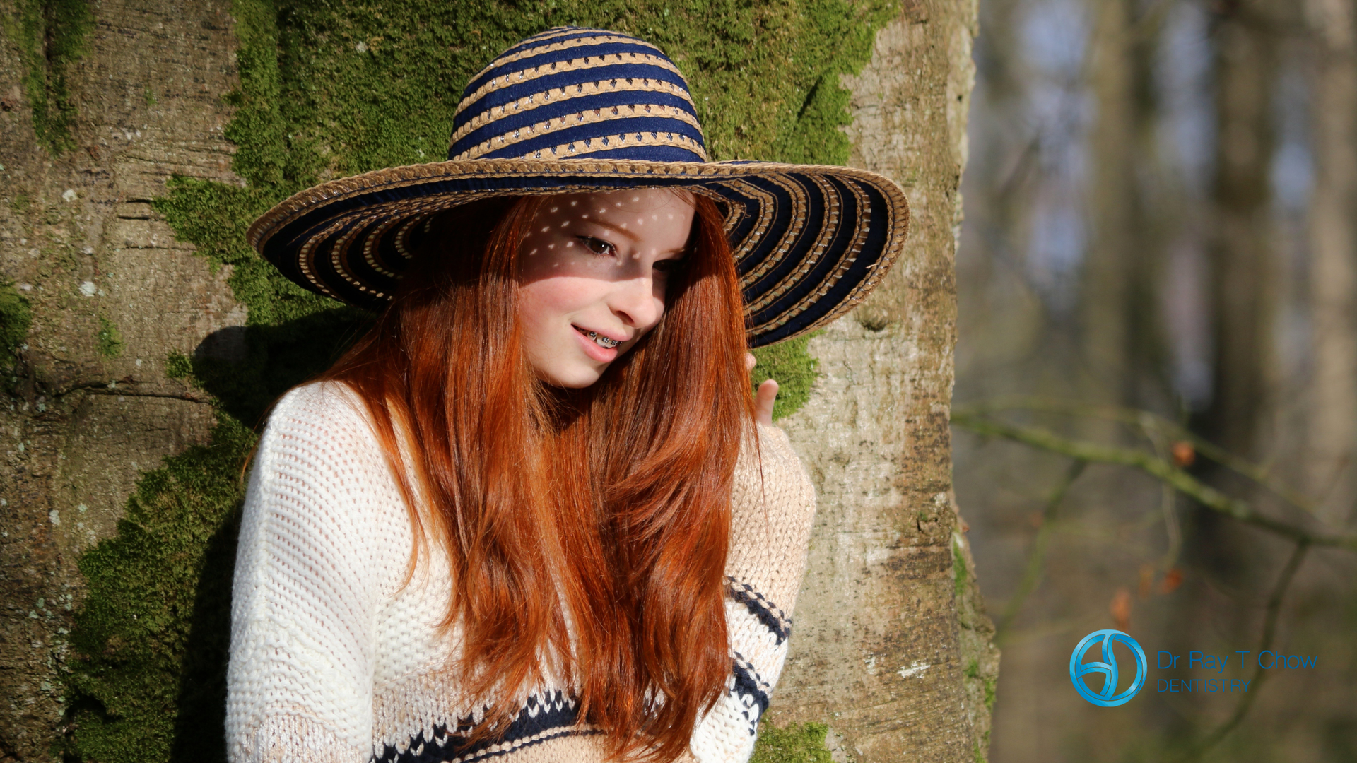 A woman wearing a hat is leaning against a tree.