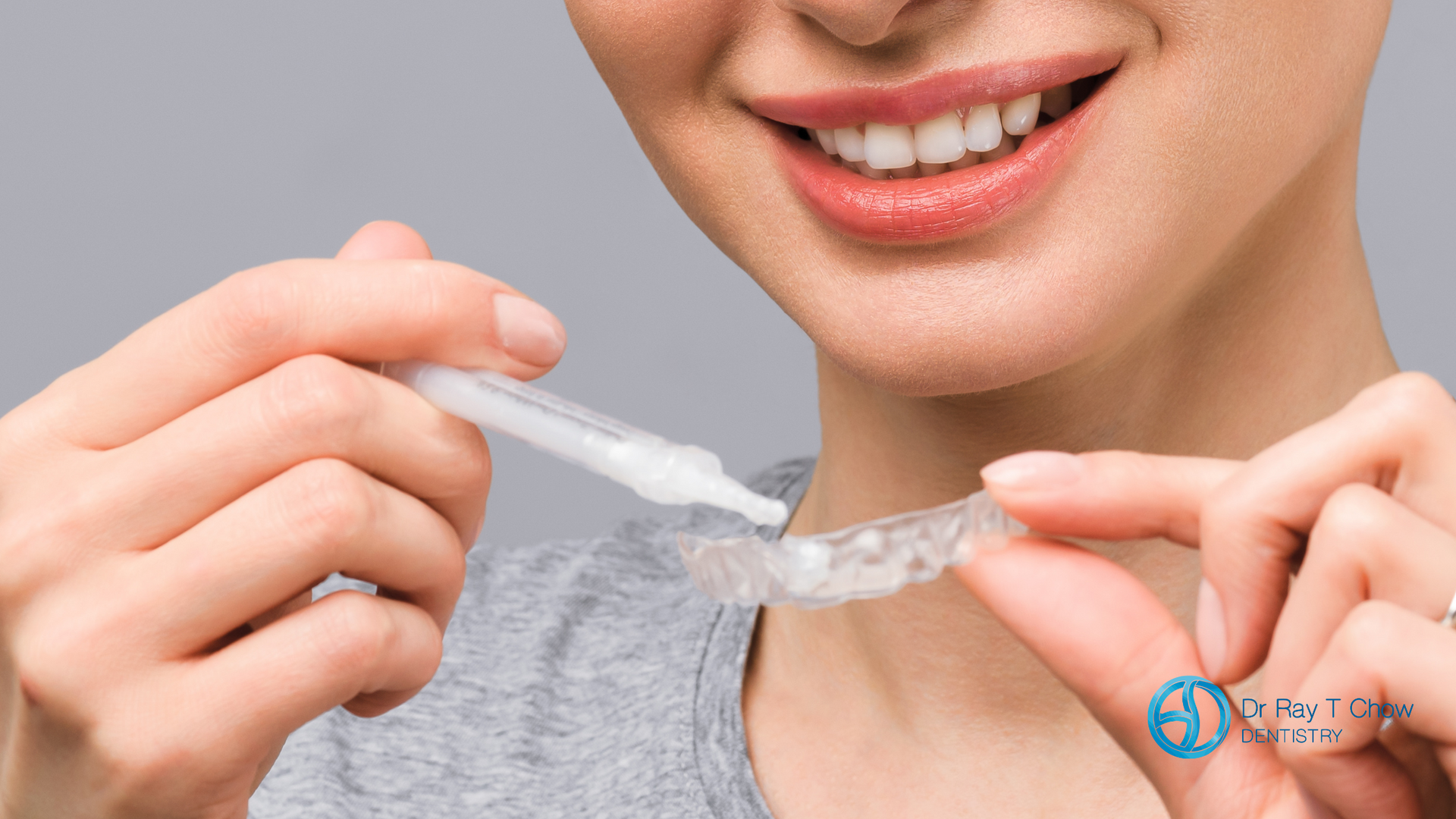 A woman is holding a tooth whitening device in her hands.