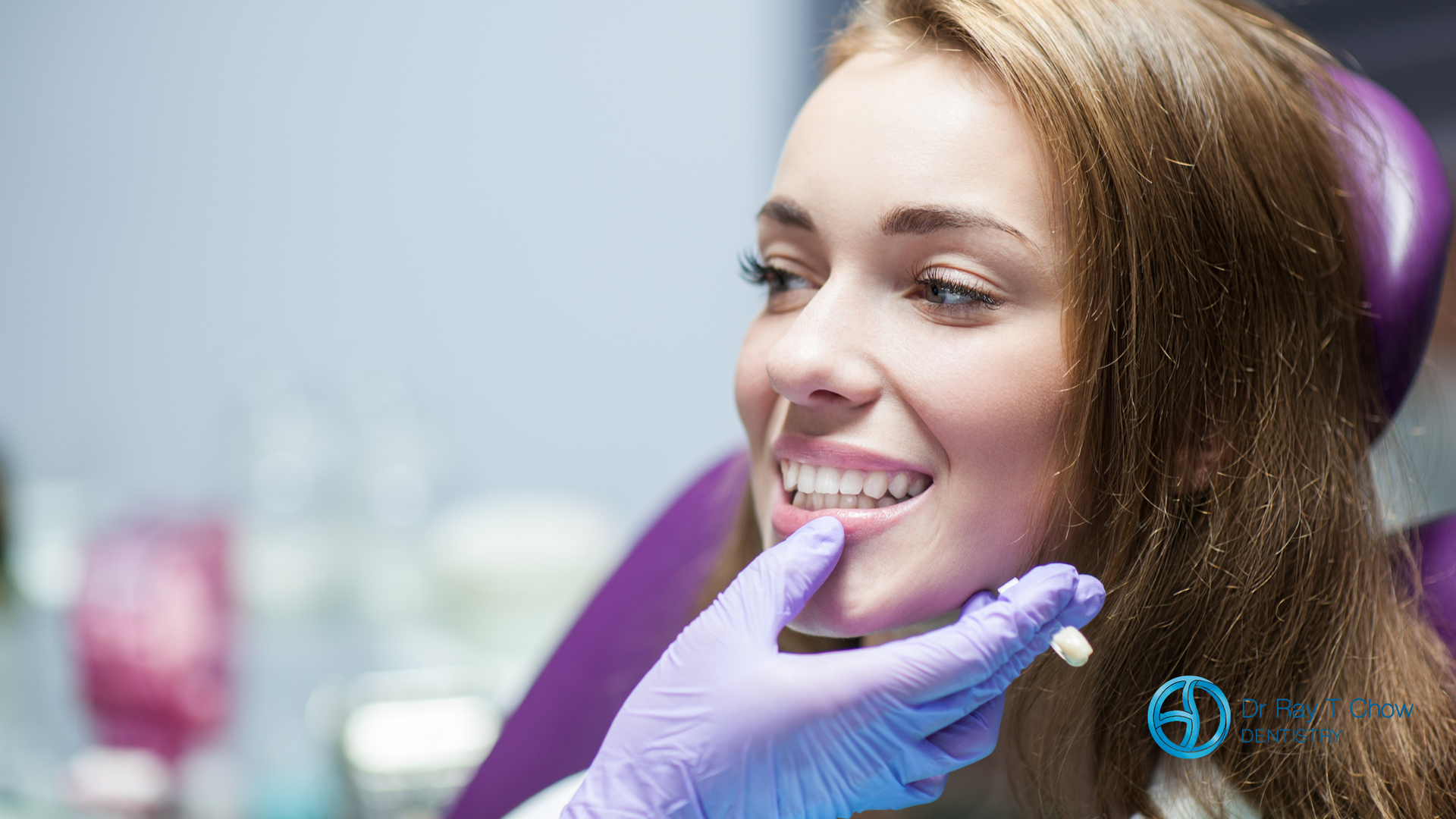 A woman is sitting in a dental chair while a dentist examines her teeth.