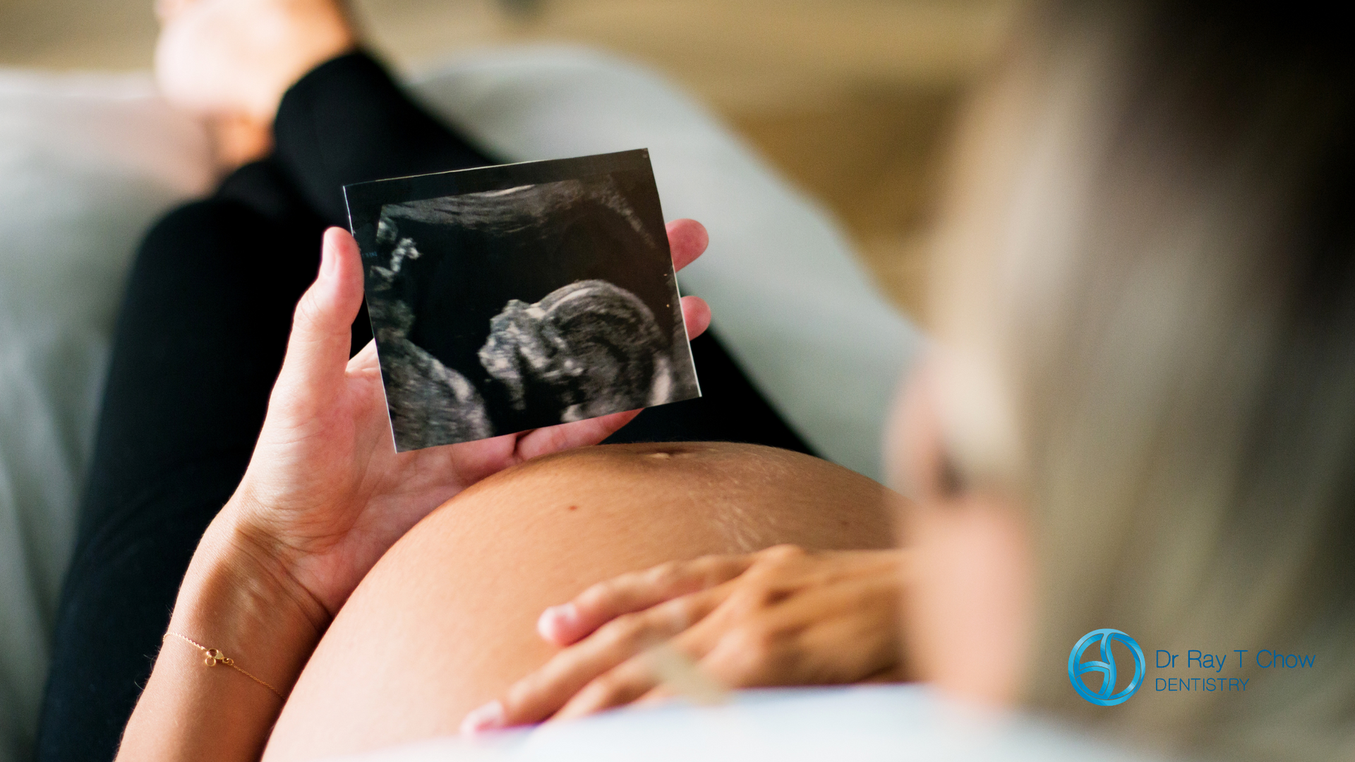 A pregnant woman is holding an ultrasound of her baby.