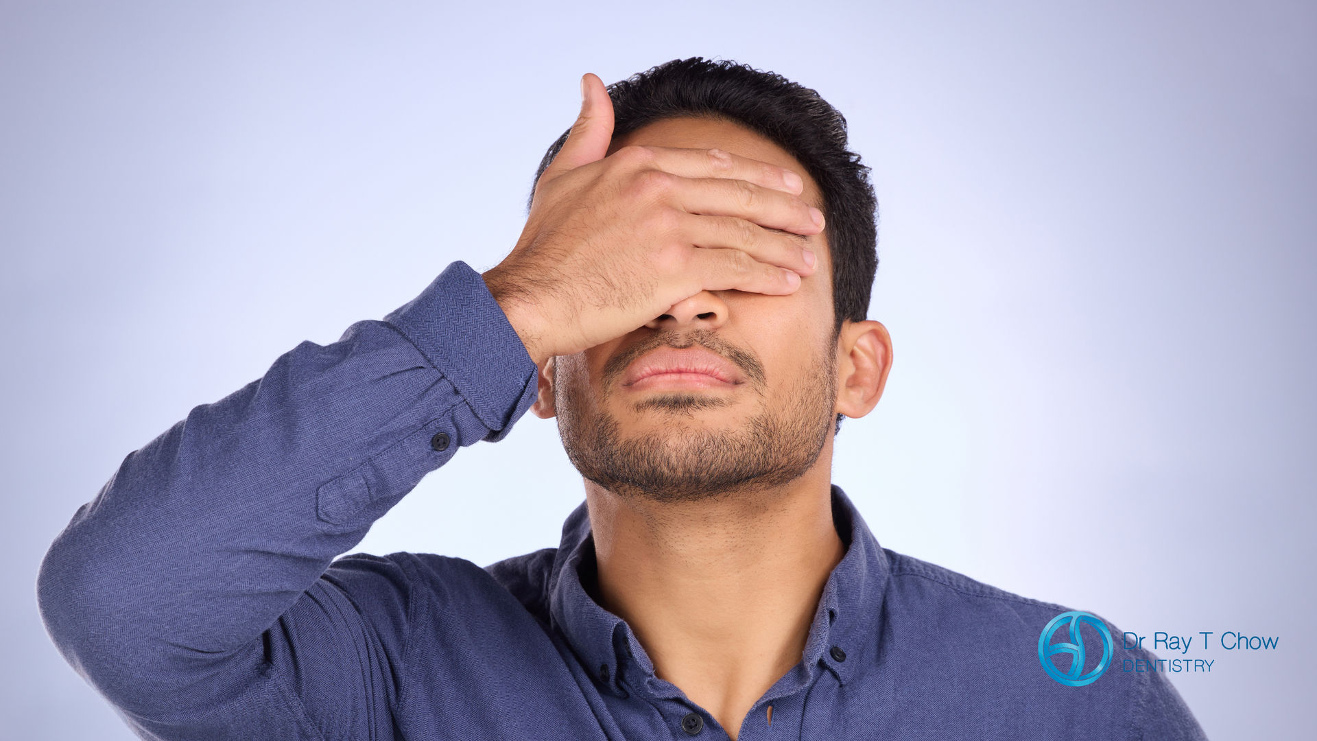 A man is covering his eyes with his hand.
