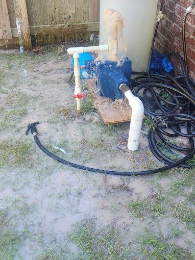 A water pump is sitting on the ground next to a hose.