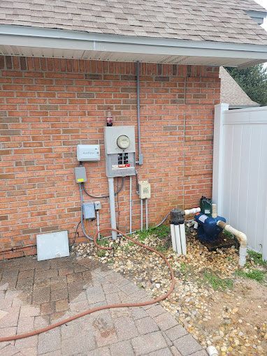 There is a hose attached to the side of a brick building.