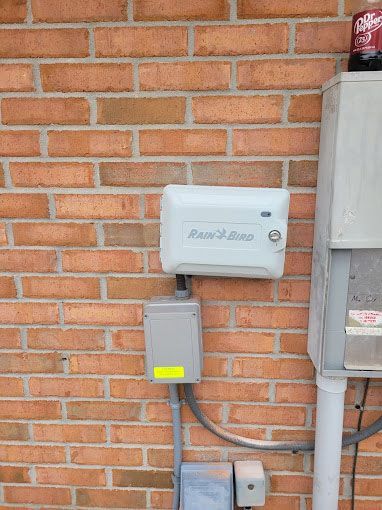 A brick wall with a white box mounted to it.