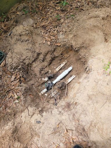 A pipe is laying in the dirt in a hole.