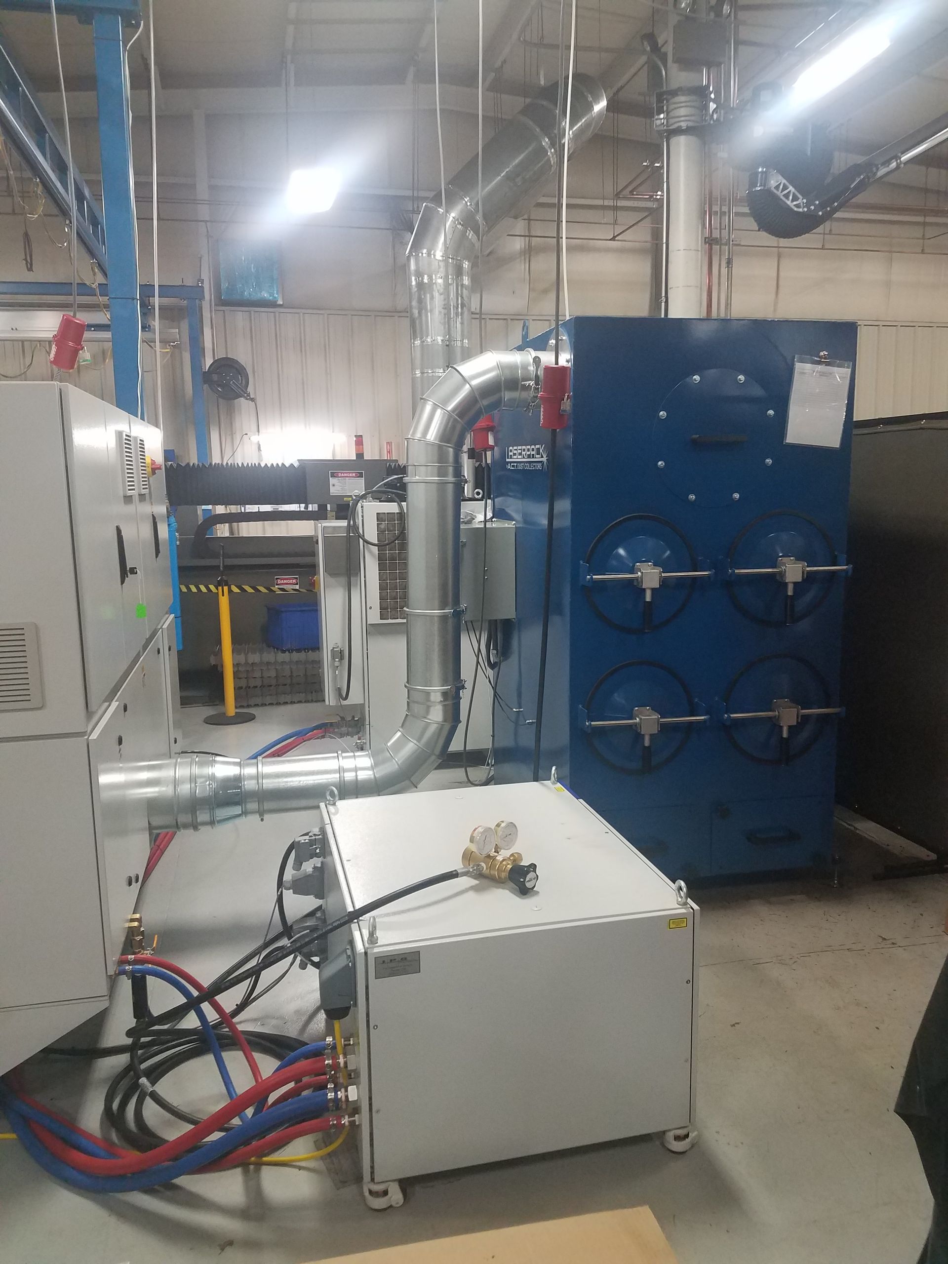 Industrial equipment with blue and white machinery, pipes, and electrical connections in a factory setting.