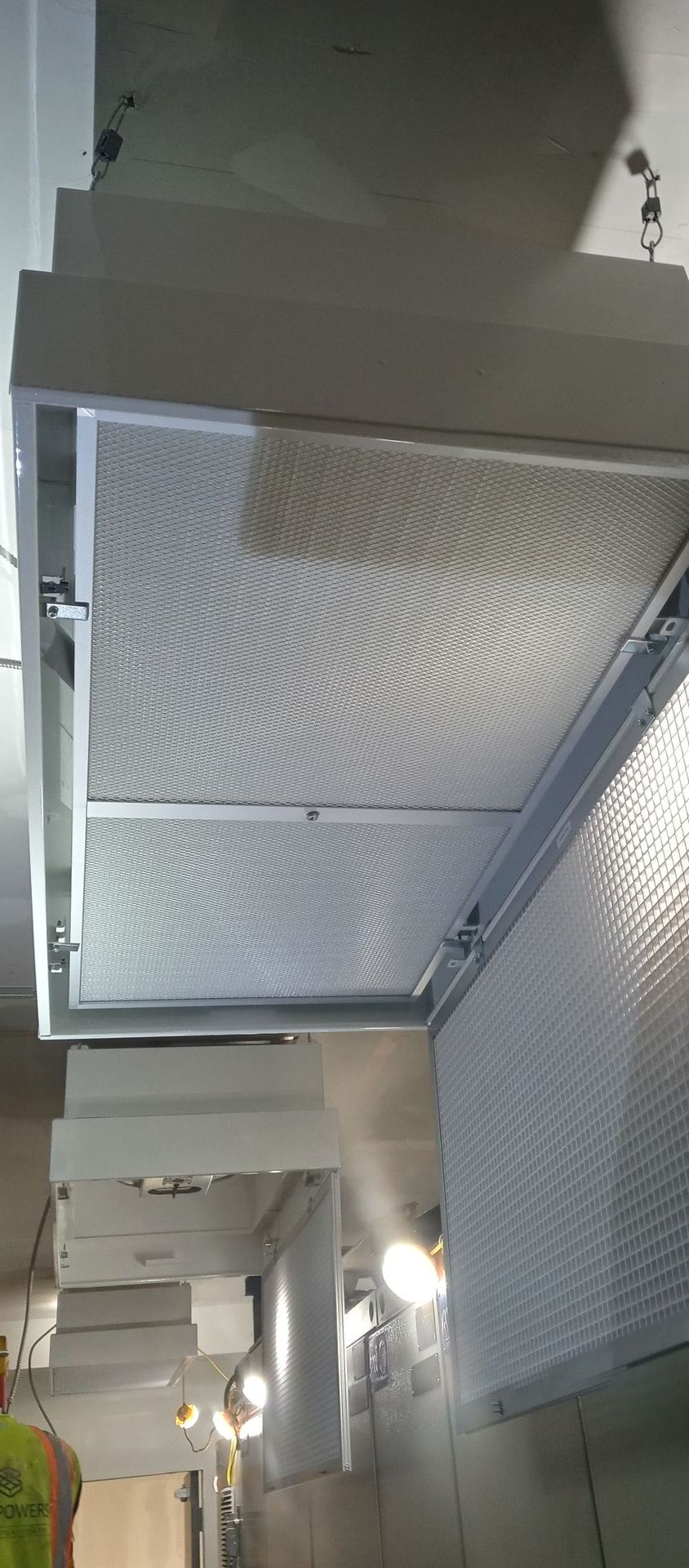Ceiling mounted air filters, with grid-like pattern, in a commercial building setting.