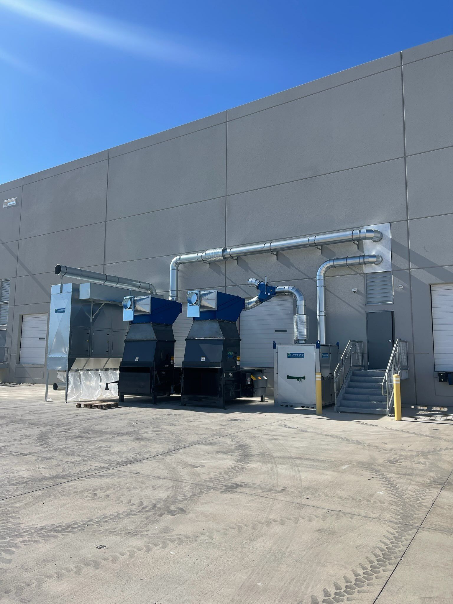 Exterior view of an industrial building with large ventilation and air purification equipment installed on the side.