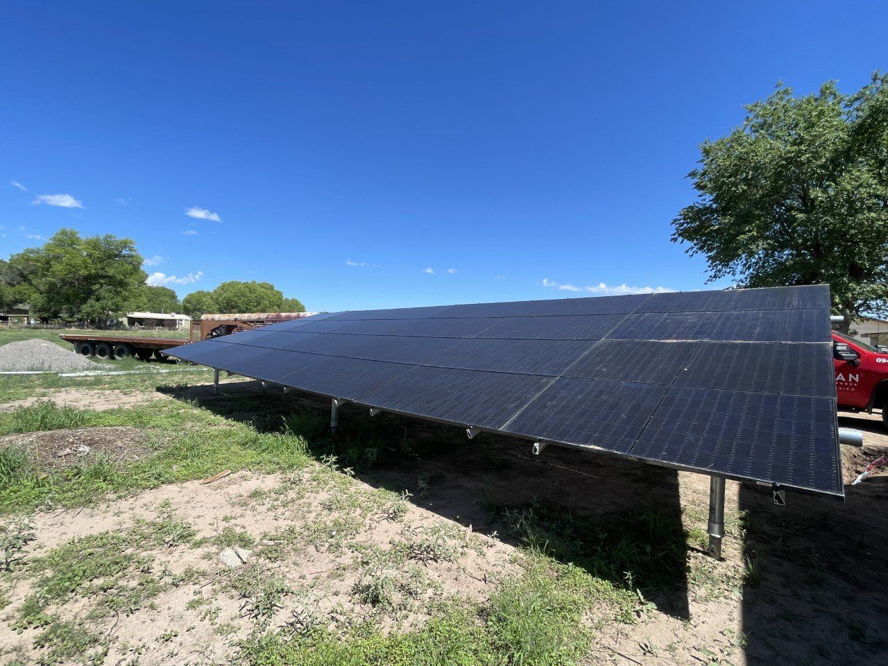 Ground-mounted solar panels in a grassy field against a blue sky.