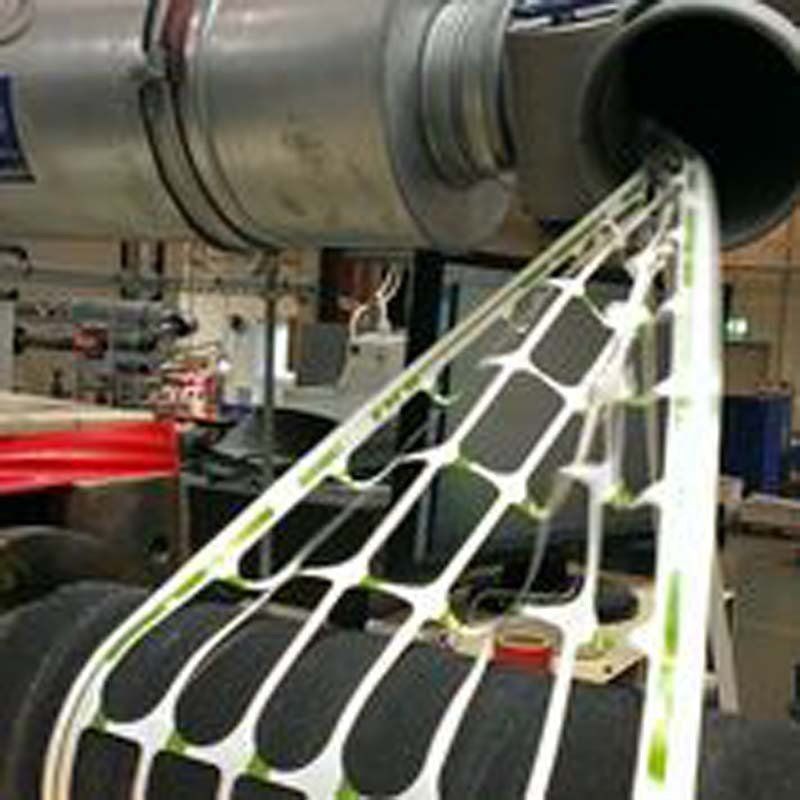 Close-up of a white, open-frame structure extending from a large cylindrical component, possibly part of an engine.