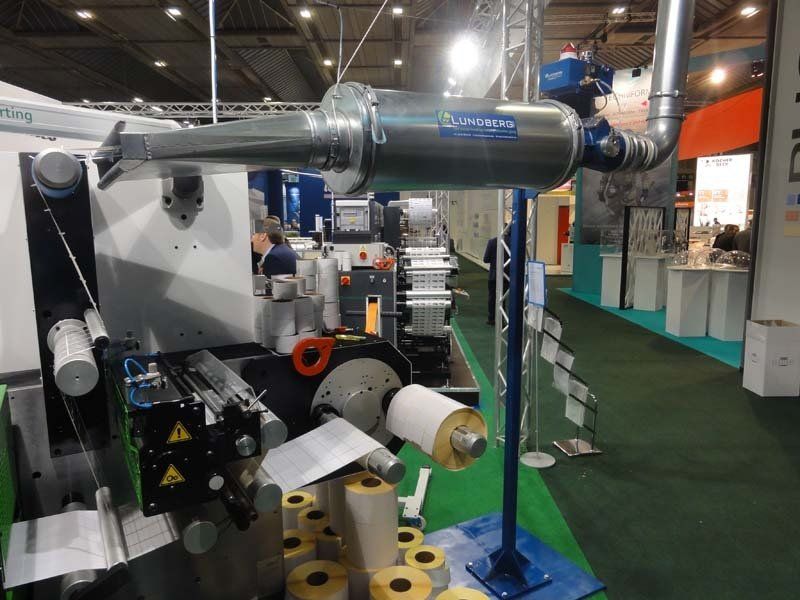 Industrial printing machine with rolls of paper, tubing, and a blue stand.